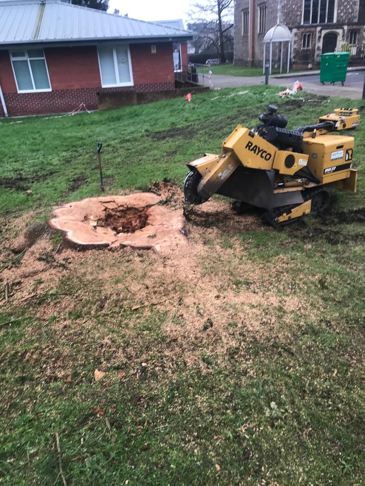 Rayco stump grinder next to a freshly ground stump on a village green